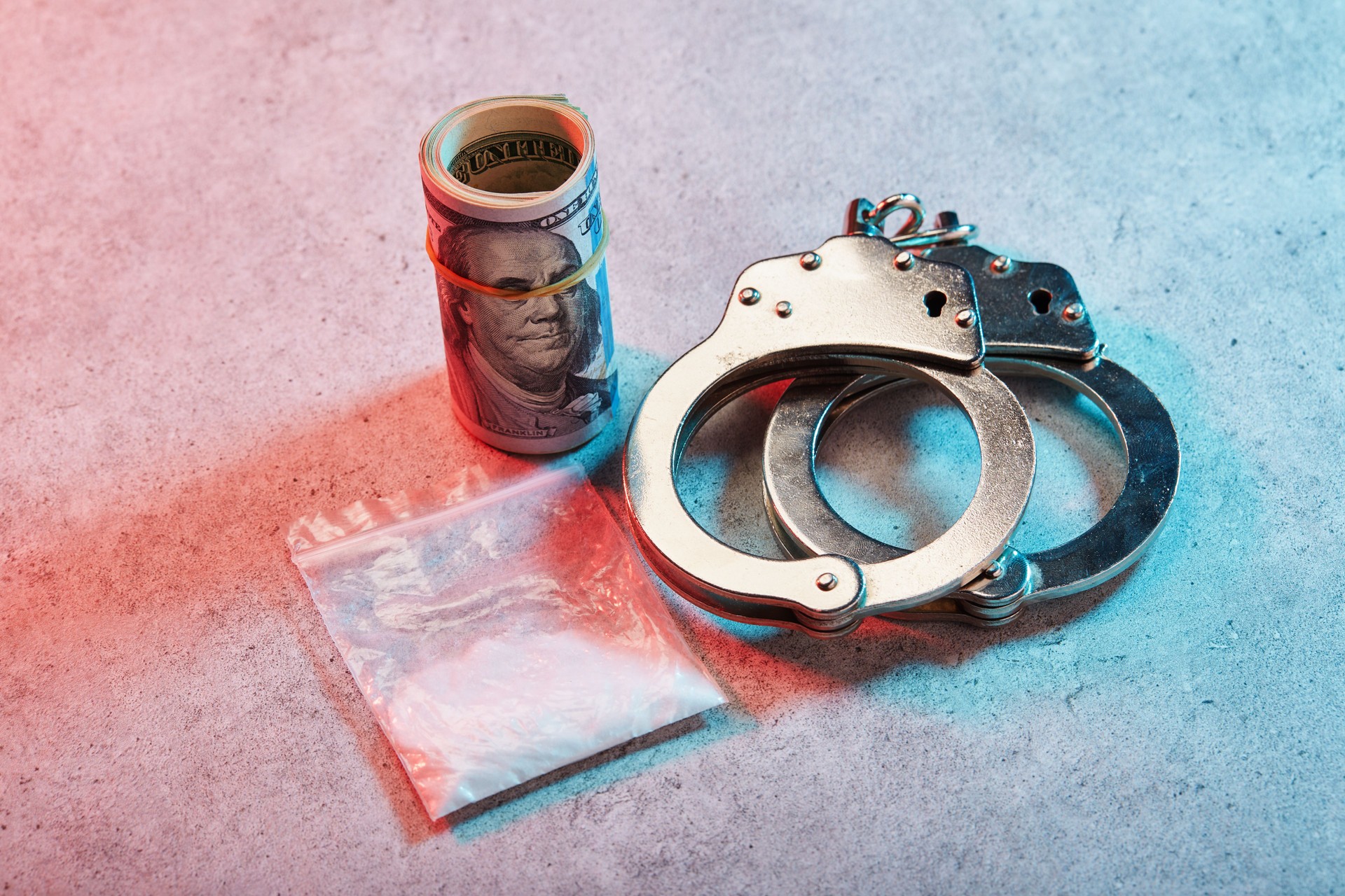 Handcuffs and roll of American one hundred dollar banknotes